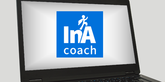 Auf dem Bildschirm eines Laptops ist das Logo von InA.Coach.