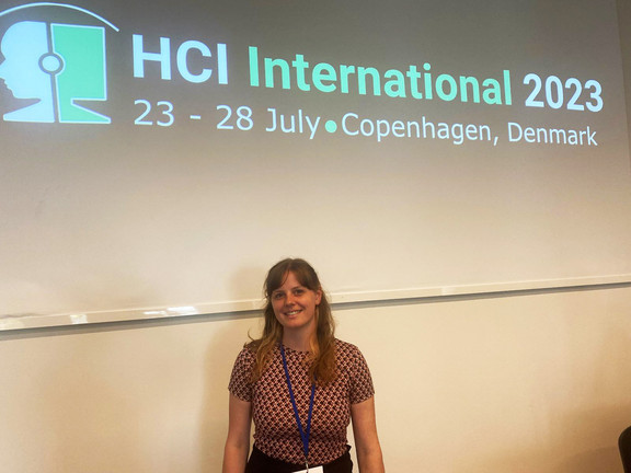 Laura Wuttke steht vor dem Schriftzug der HCI International 2023
