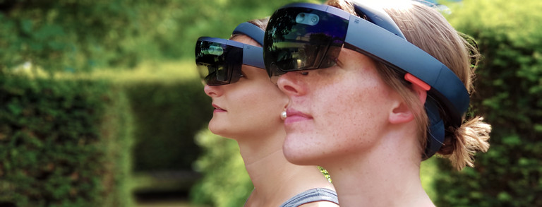 Zwei weibliche Personen, die draußen eine HoloLens tragen und in die gleiche Richtung schauen.
