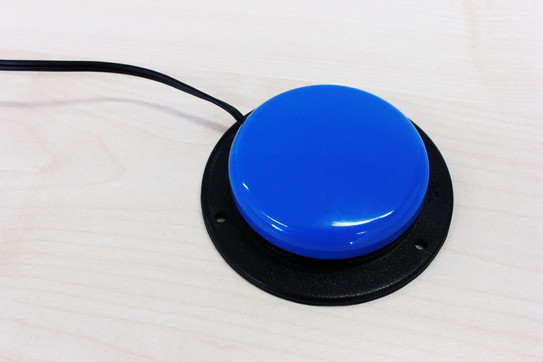 Ein blauer Taster mit einem schwarzen Gehäusekranz. Er ist an ein Kabel gebunden.