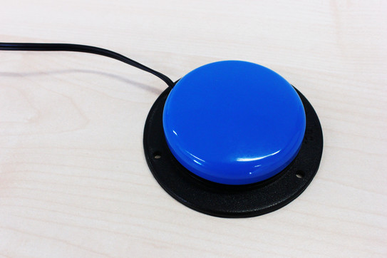 Jelly Bean Switch Ein blauer Taster mit einem schwarzen Gehäusekranz. Er ist an ein Kabel gebunden.