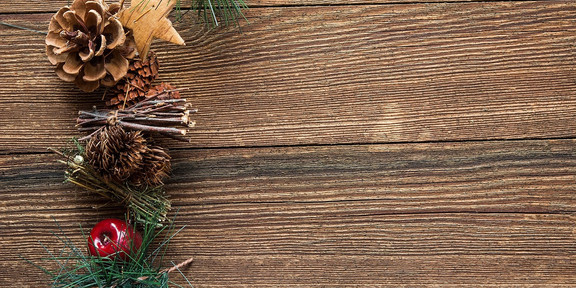 Bild Weihnachtswünsche Ein weihnachtliches Gesteck aus Tannenzapfen, roten Beeren, Tannenzweigen, Hölzern und Sternen.