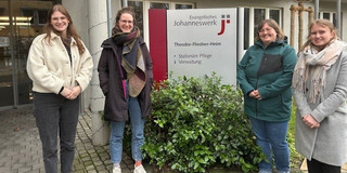 Foto von vier Mitarbeiterinnen des EVE4all-Projektes vor dem Theodor-Fliedner-Heim. Zwei Personen stehen jeweils rechts und links von einem Schild, auf dem steht: Evangelisches Johanneswerk, Theodor-Fliedner-Heim.