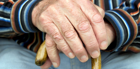 Detailaufnahme eine ältere Person hält einen Gehstock fest.