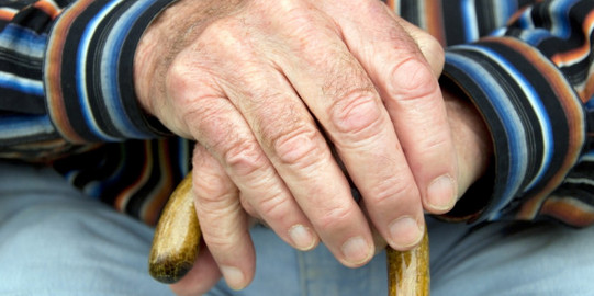 Detailaufnahme eine ältere Person hält einen Gehstock fest.