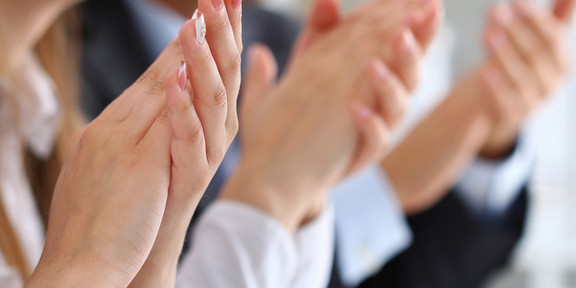 Several hands of women and men clap.